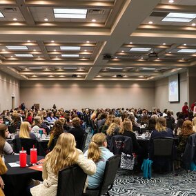 Attendees of conference sit in ballroom during presentation