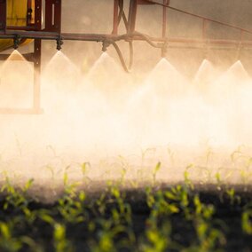 Tractor spraying pesticide onto field