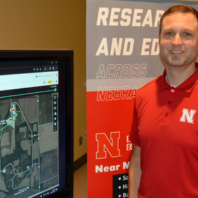 Nate Thorson stands beside screen displaying ag software