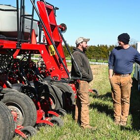 Two farmers conversing near farm equipment