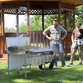 Man stands near rainfall simulator during presentation