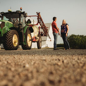 Man and woman speaking near tractor