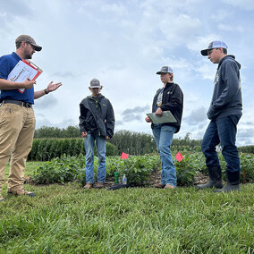 Adult speaks to three youth in field