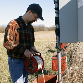 Man holds cable reel above water well