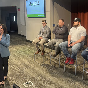 Woman stands in front of panel sitting on stage