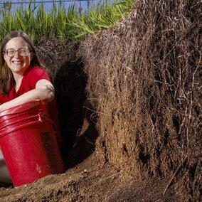 Woman sits near wall of soil