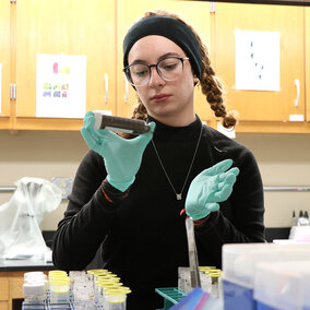 Woman examines specimen tube in laboratory