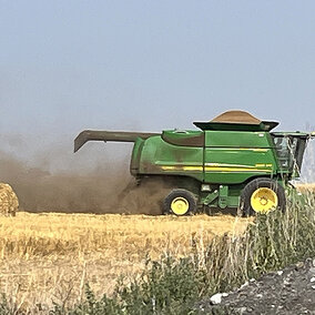 Combine moving in field as black dust rises