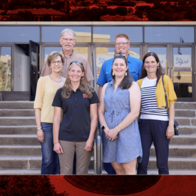 Six people stand on steps in front of building