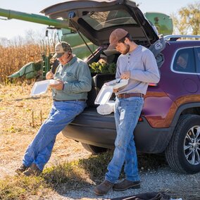 Two men look at paperwork near field