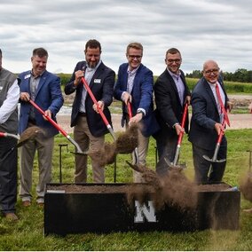 Men hold shovels behind ceremonial dig area