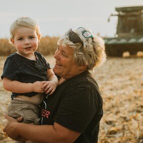 Woman holds young boy on farm