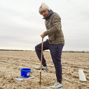 Man sampling soil in field