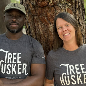 Man and woman pose in front of tree