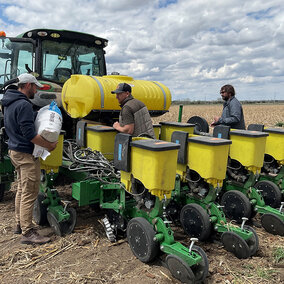 Three men work at a planter in the field