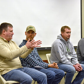 Four Nebraska farmers sit on a discussion panel, with one speaking and gesturing as others listen during a nitrogen management Q&A about Sentinel Ag.