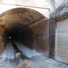 Closeup of empty canal tunnel entrance and tumbleweeds on ground