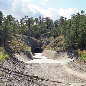 Wide angle photo of empty canal tunnel during summer, surrounded by green trees