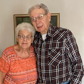 Don and Mary Lee Gasper stand side by side and smile for a photo inside their home