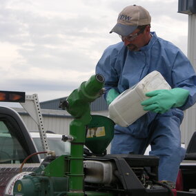 Photo of gloved pesticide applicator