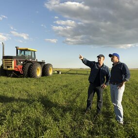 two farm employees discuss plans in a field