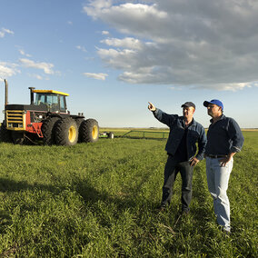 Standing in a field an employer shows a new employee the 