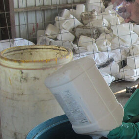 Lucas Burch wears gloves and safety glasses while triple rinsing a pesticide container.