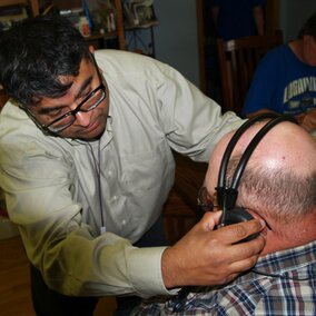 A researcher from the UNMC Center for Public Health works with a Nebraska farmer to fit protective ear wear.