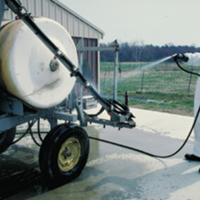 Dressed in personal protective gear and cleaning a sprayer