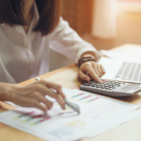 Woman analyzing spreadsheets and using calculator