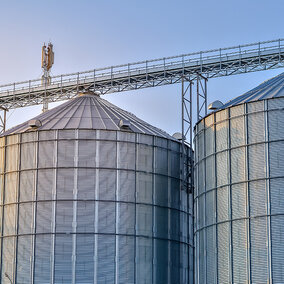 Silver grain bins stacked closely together under blue sky