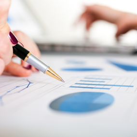 Woman holds pen above bar chart on paper