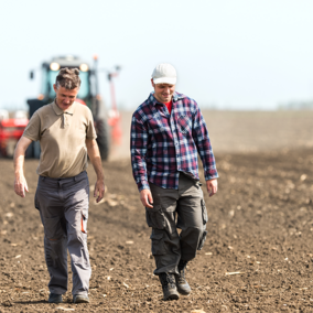 Two men smiling and walking side-by-side in field