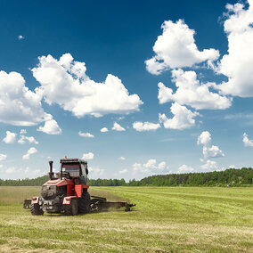 tractor harvests hay in pasture