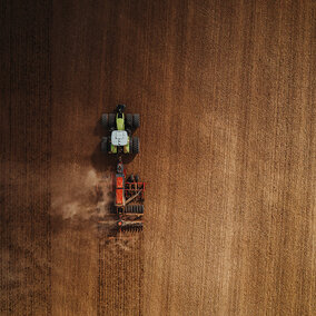 Tractor pulls planter through field during wheat planting