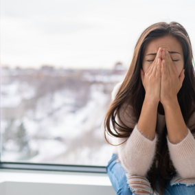 Woman with signs of stress in front of window during winter