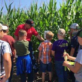 Figure 1. Extension Educator Chuck Burr demonstrating to youth how a crop moisture sensor works in a field of corn.