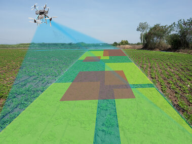 A drone equipped with sensors flies over a crop field, projecting a scanning beam that maps the field with overlaid color-coded zones indicating variations in crop health or soil conditions.