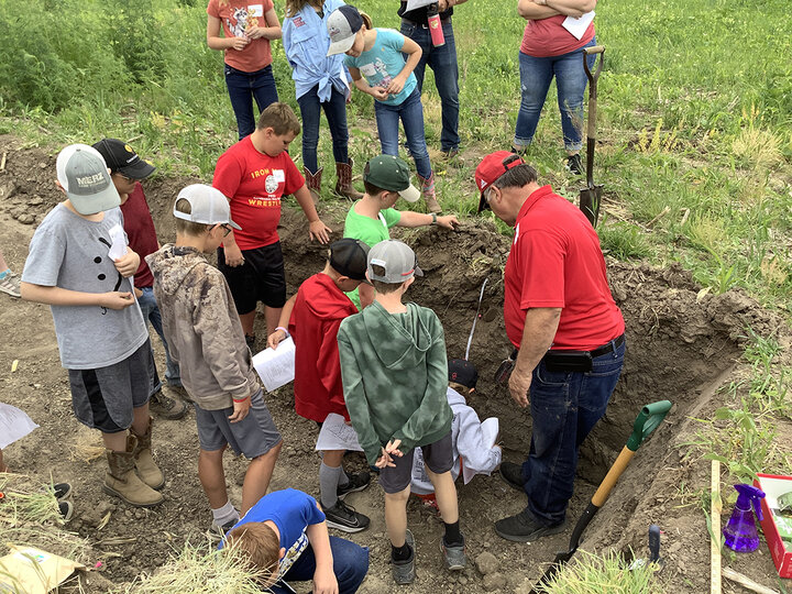 Children and adult stand in and around soil pit