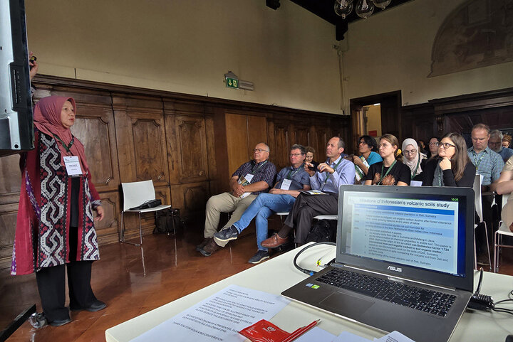 Attendees listen to woman speaking at front of room