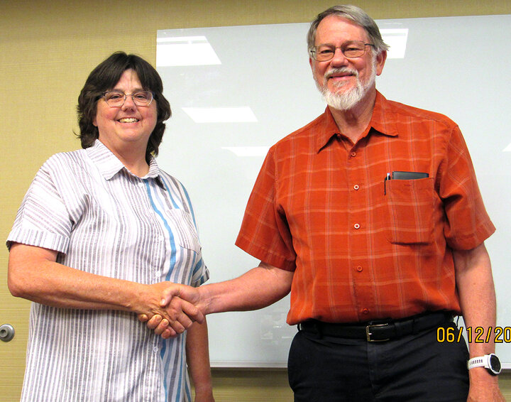 Two people shake hands toward camera