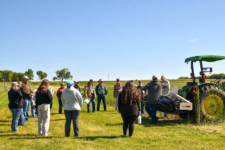 Attendees gather around a roller crimper during a live demonstration at ENREEC.