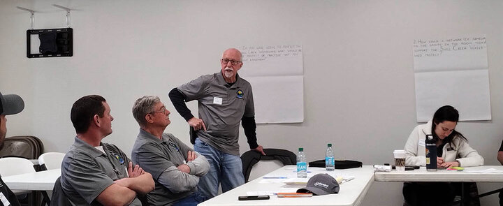 A Shell Creek Watershed member speaks while standing, as others listen and take notes during a small group discussion at the March 11 workshop