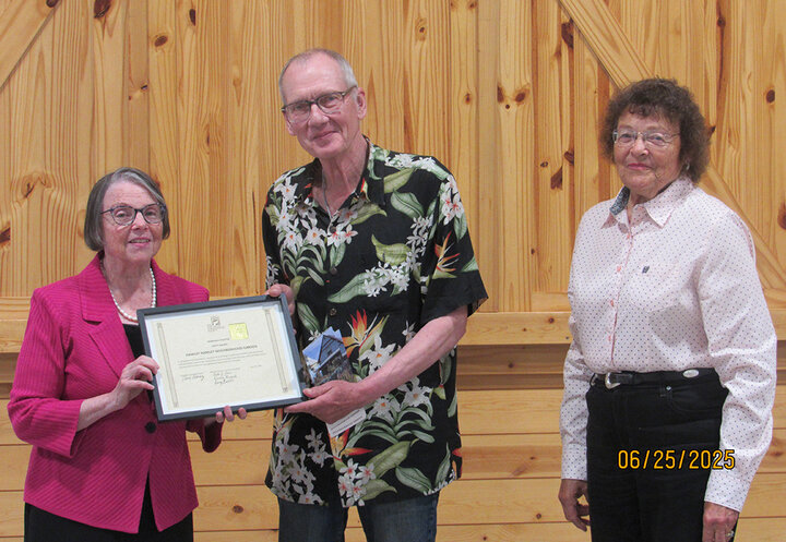 Two recipients stand with a presenter after receiving a Nebraska SWCS Merit Award; indoor group photo.