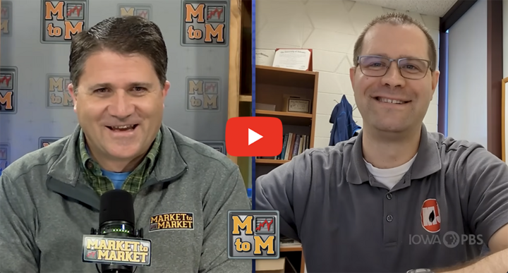 Two men speak during a Market to Market video call; the host sits at a studio desk and Eric Hunt joins from his office, smiling at the camera.