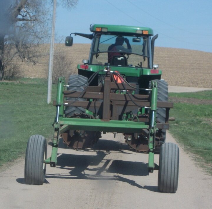 The rolling-crimper in transport down a country road.