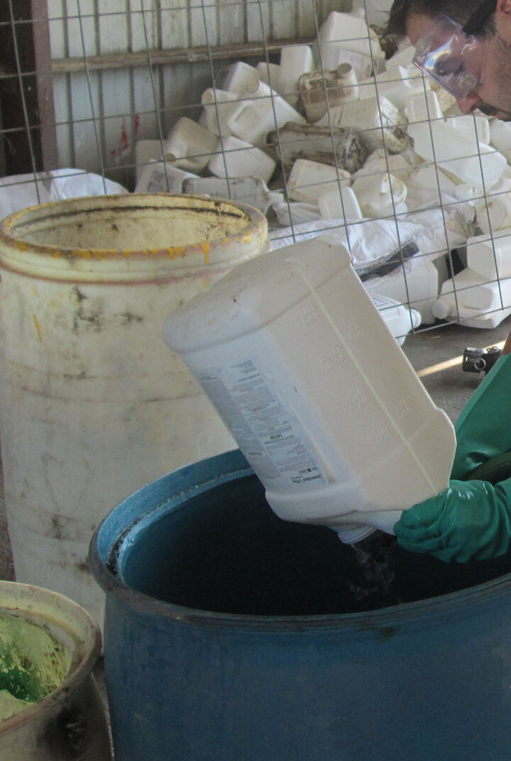 Lucas Burch wearing safety glasses while triple rising an ag pesticide container