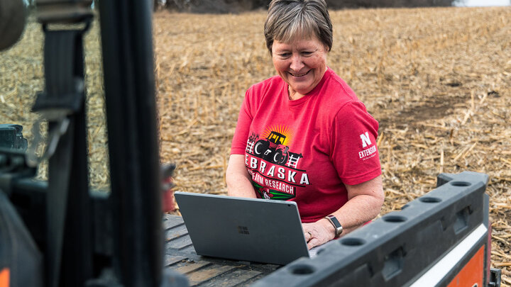 woman uses laptop in crop field