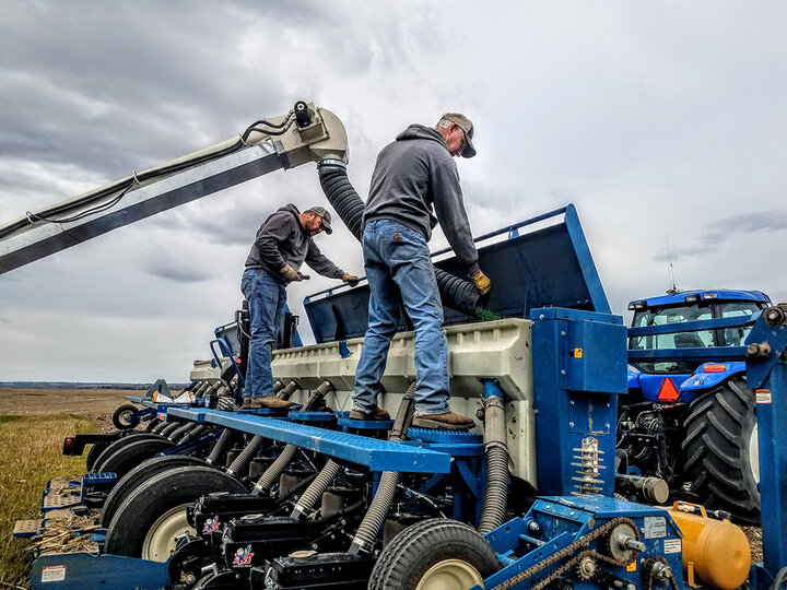 men work on seeder repairs in field