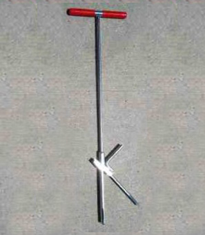 Pogostick-like soil sampler, with red handlebar grips, laying on concrete.